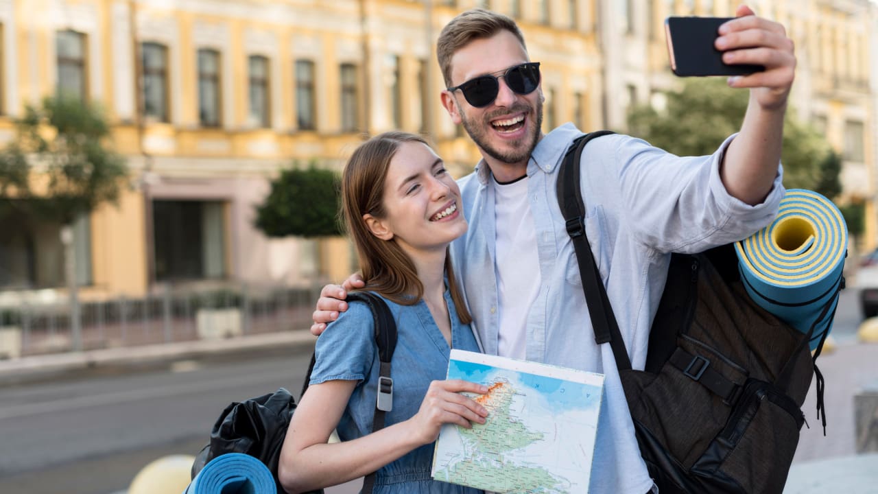 A couple taking selfie while carrying their backpacks and essentials