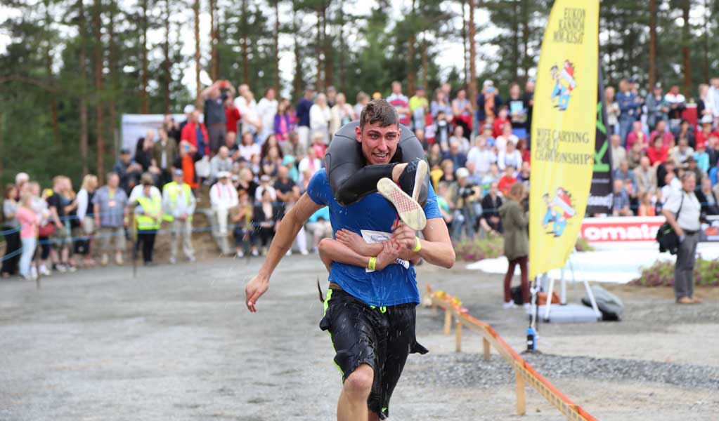 a man is running while carrying his wife upside down in Wife Carrying sport