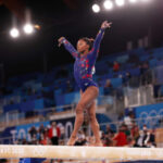 a girl is standing on a beam and doing aerobic skills