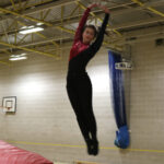 a girl is doing a turning jump which is an important skill for a gymnast