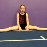 a girl is doing straddle sit which is an acrobatics skill