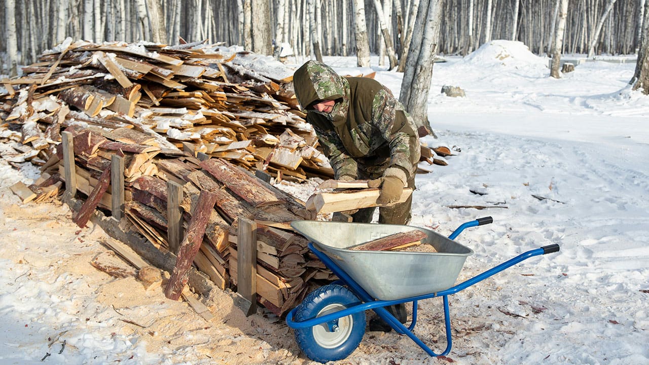 A Man Getting Woods of Tree Logs on the Snow-Covered Ground