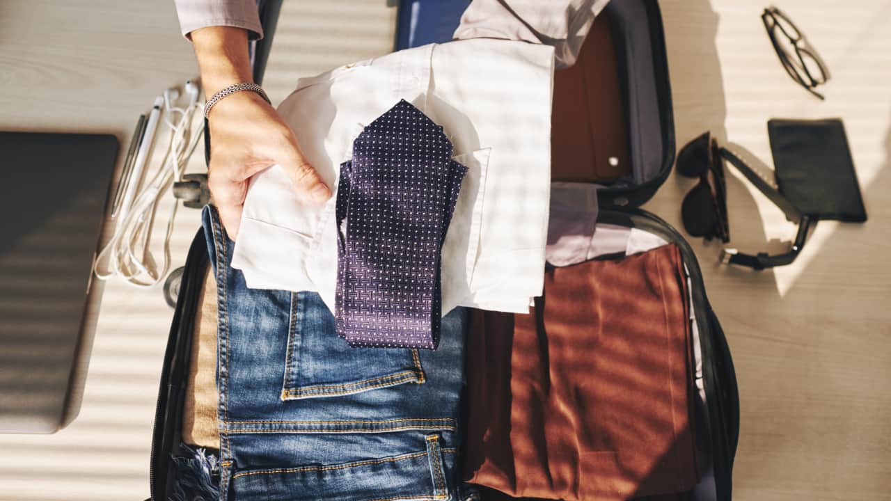 A man packing clothes in a bag