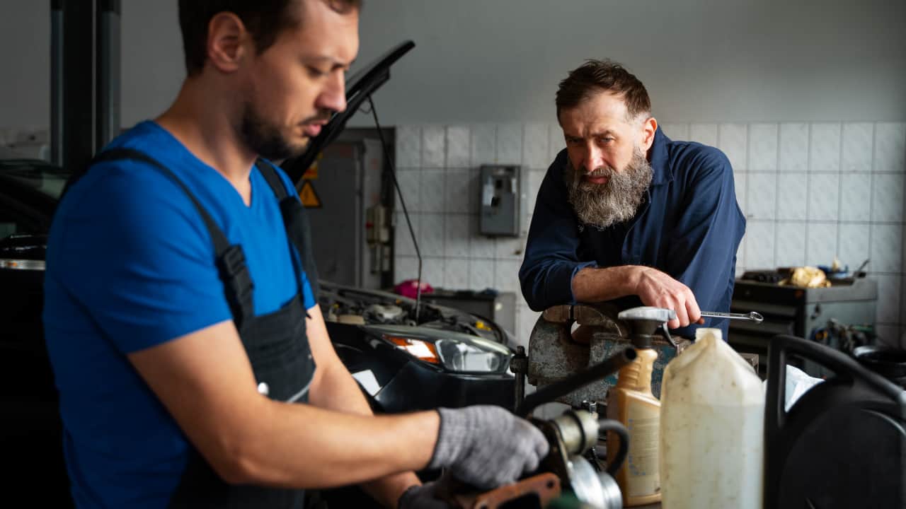 Two male mechanics working together at the workshop