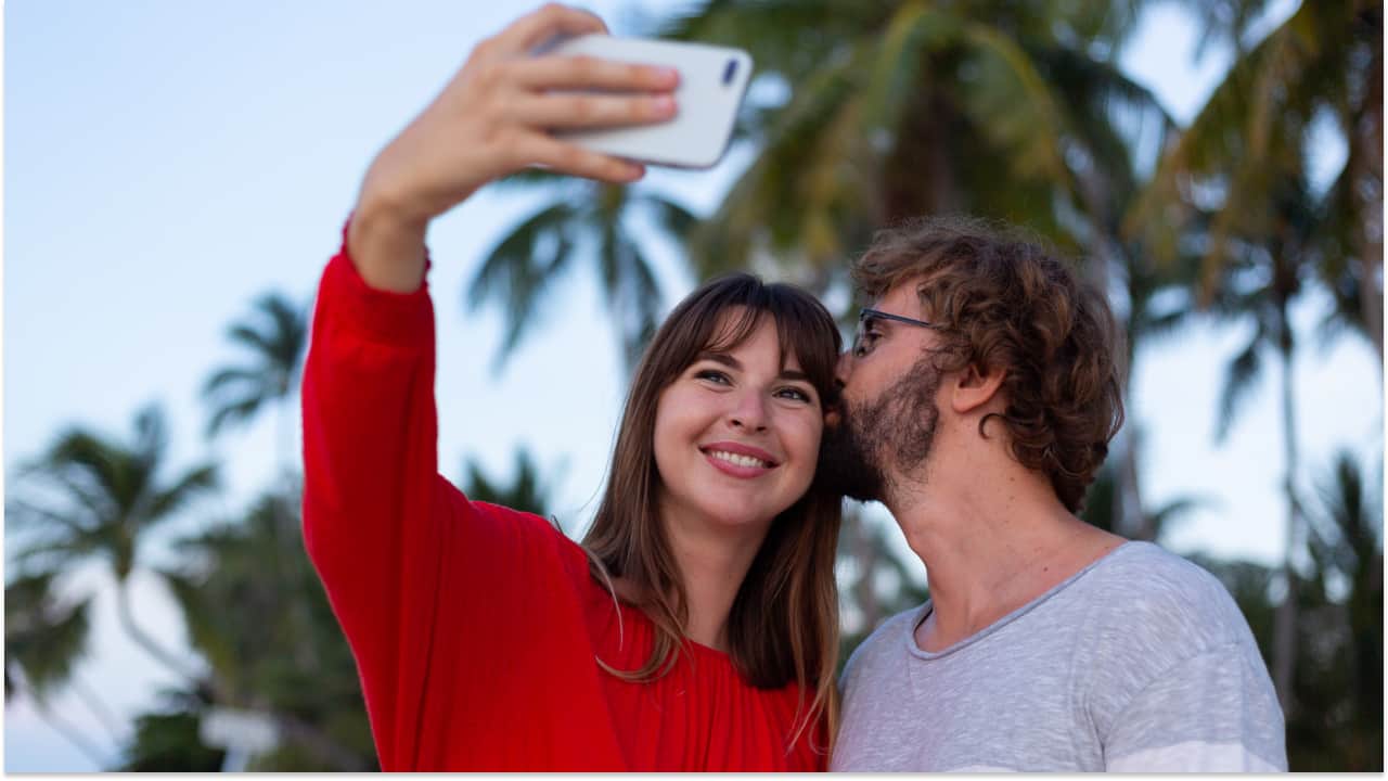 a girl is taking a selfie with a boy who is kissing her forehead